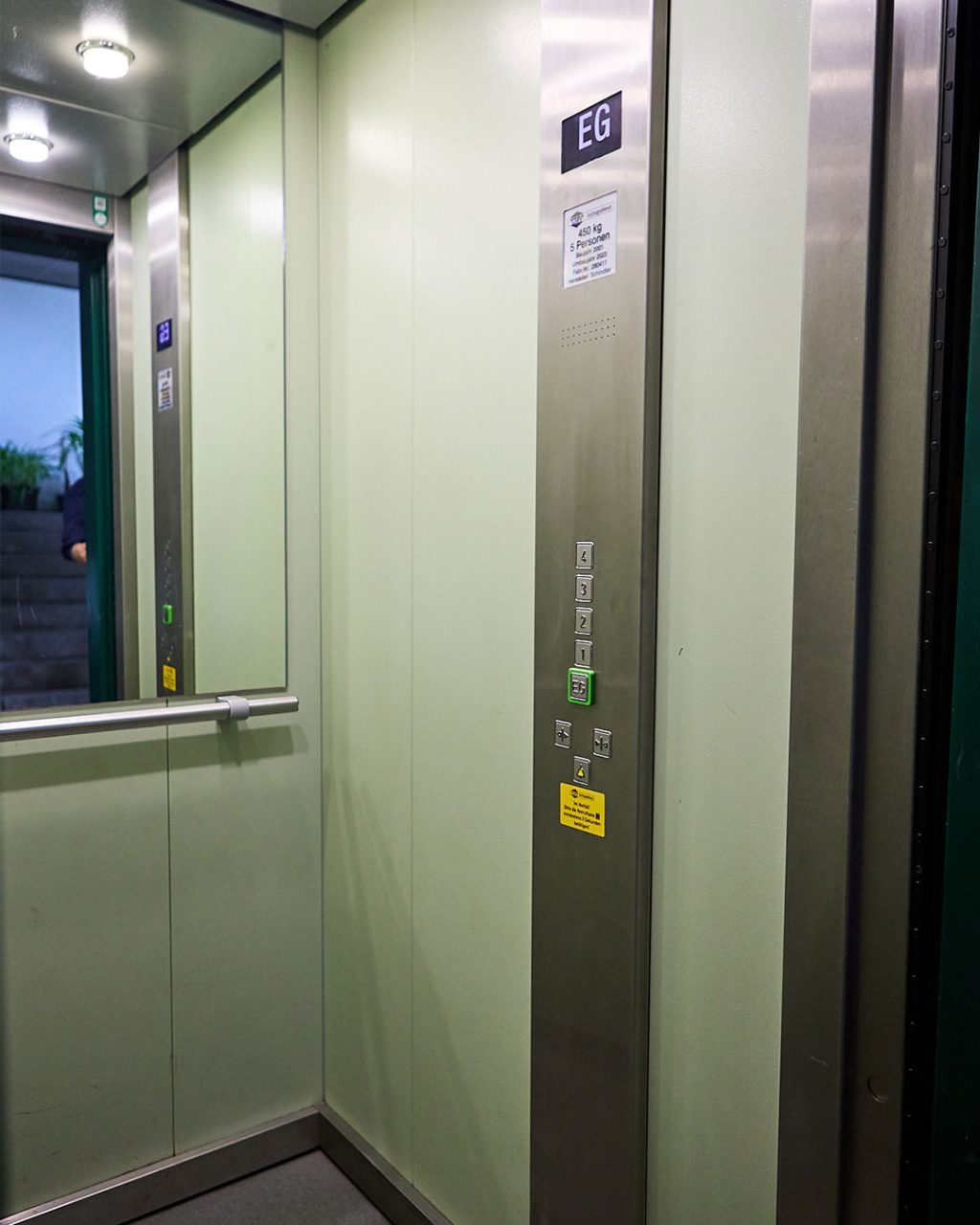 Innenansicht der Aufzugskabine mit Bedienpanel, Spiegel und Handlauf. Angabe zur Kapazität (450 kg, 6 Personen) in einem Orba lift Aufzug