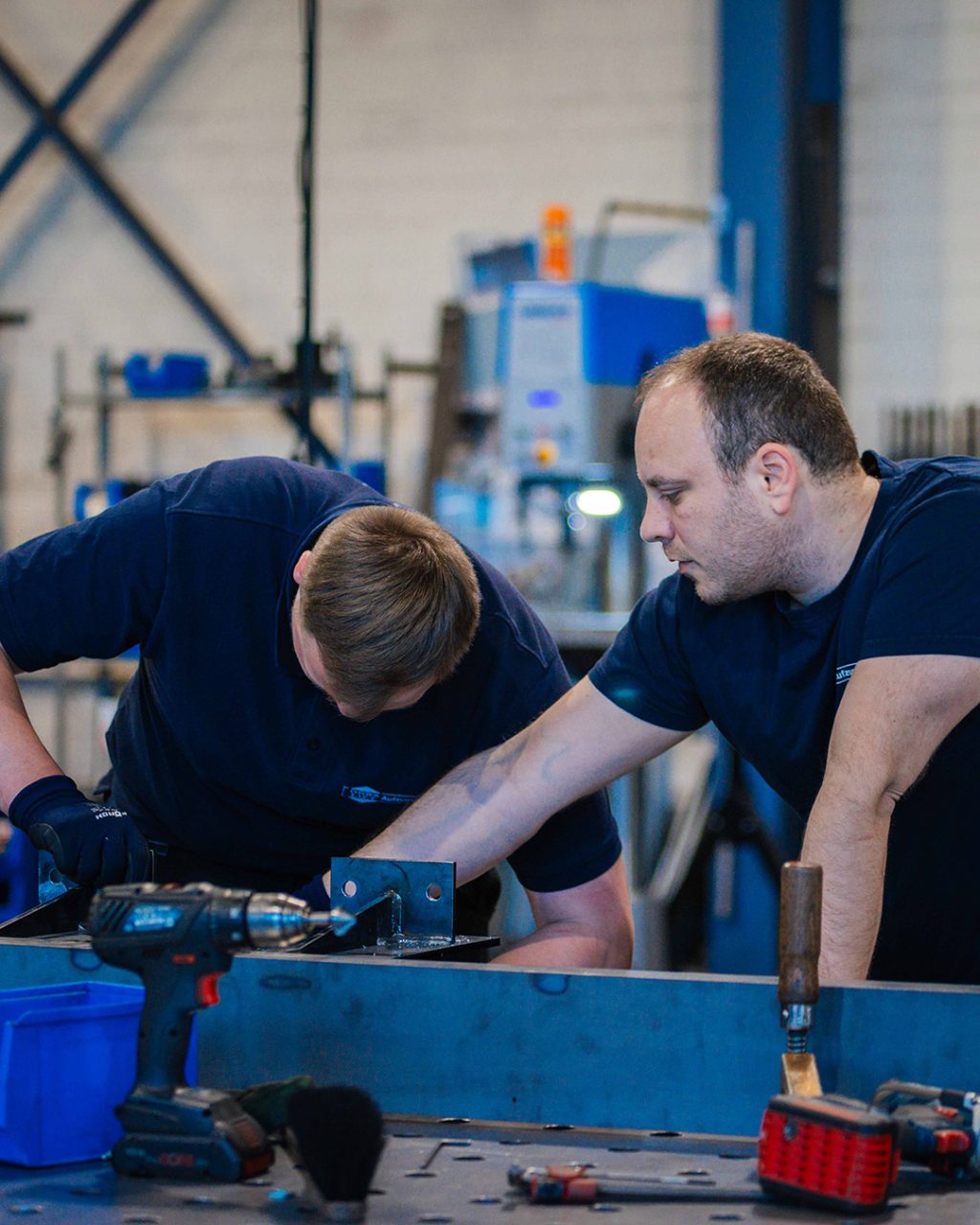 Mitarbeiter zeigt Azubi wie er Werkstück bearbeiten soll