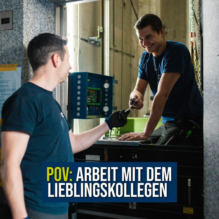 Zwei ORBA Mitarbeiter modernisieren einen Aufzug. Ein Mitarbeiter sitzt auf der Aufzugskabine im Aufzugsschacht, der andere überreich Werkzeug