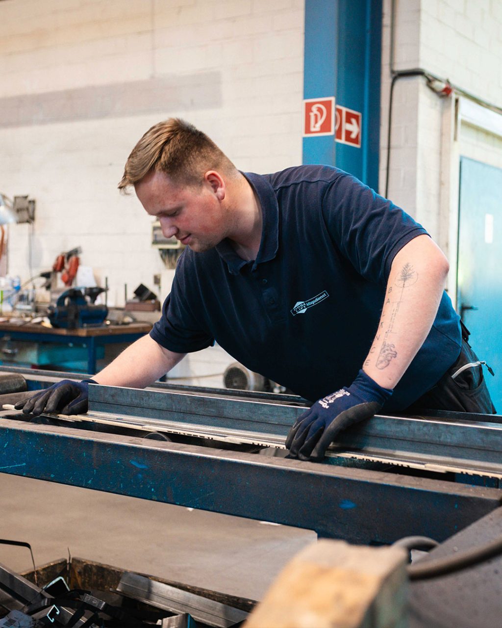Ein Handwerker richtet ein Metallprofil an einem Arbeitstisch in der Werkstatt aus.
