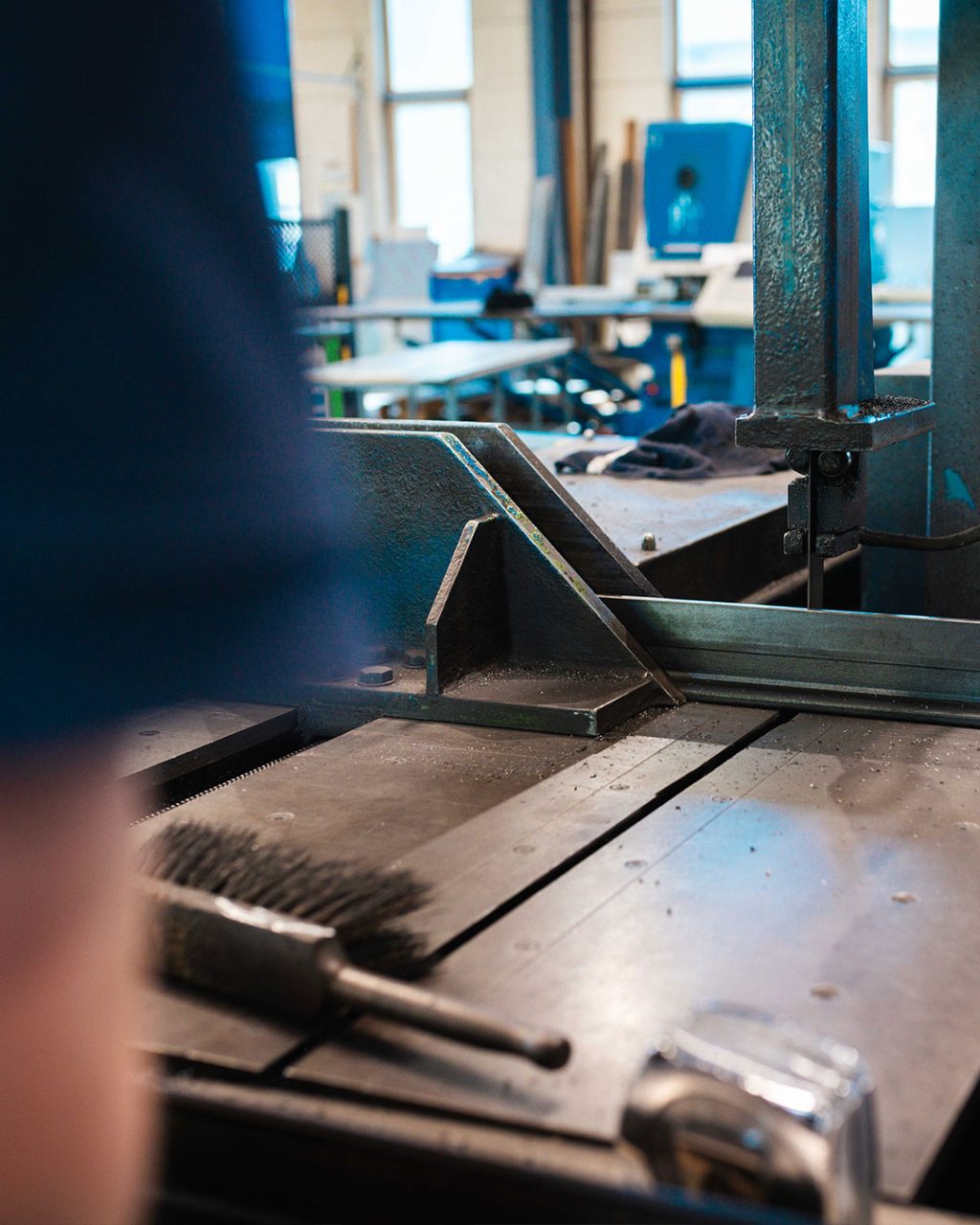 Nahaufnahme einer Metall-Bandsäge und eines Arbeitstisches in einer Werkstatt.